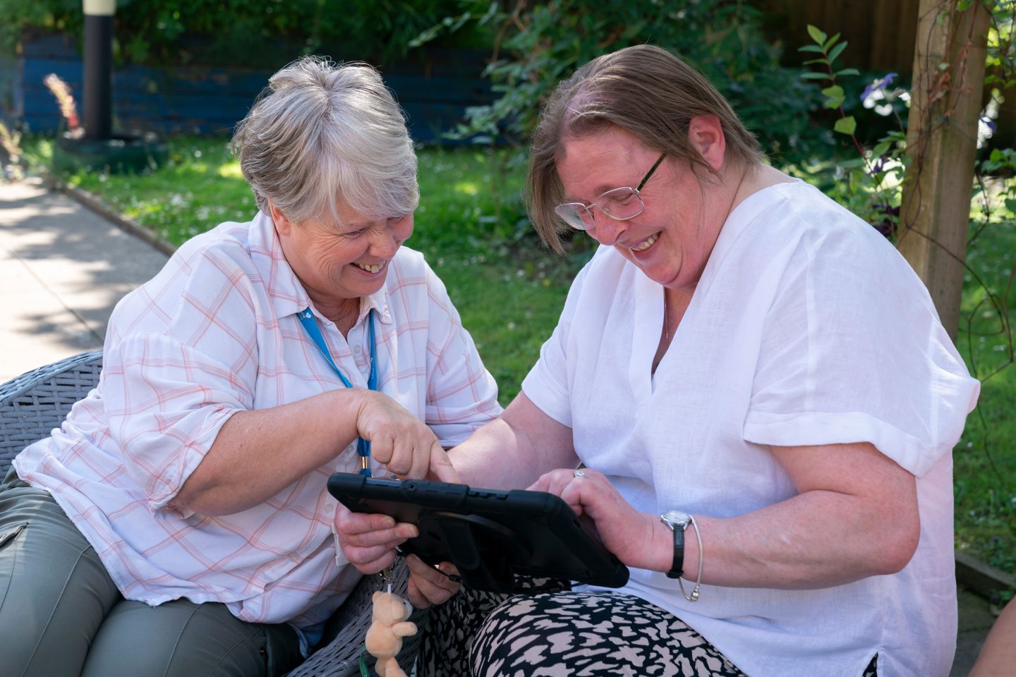 Two people sat outside looking at tablet device